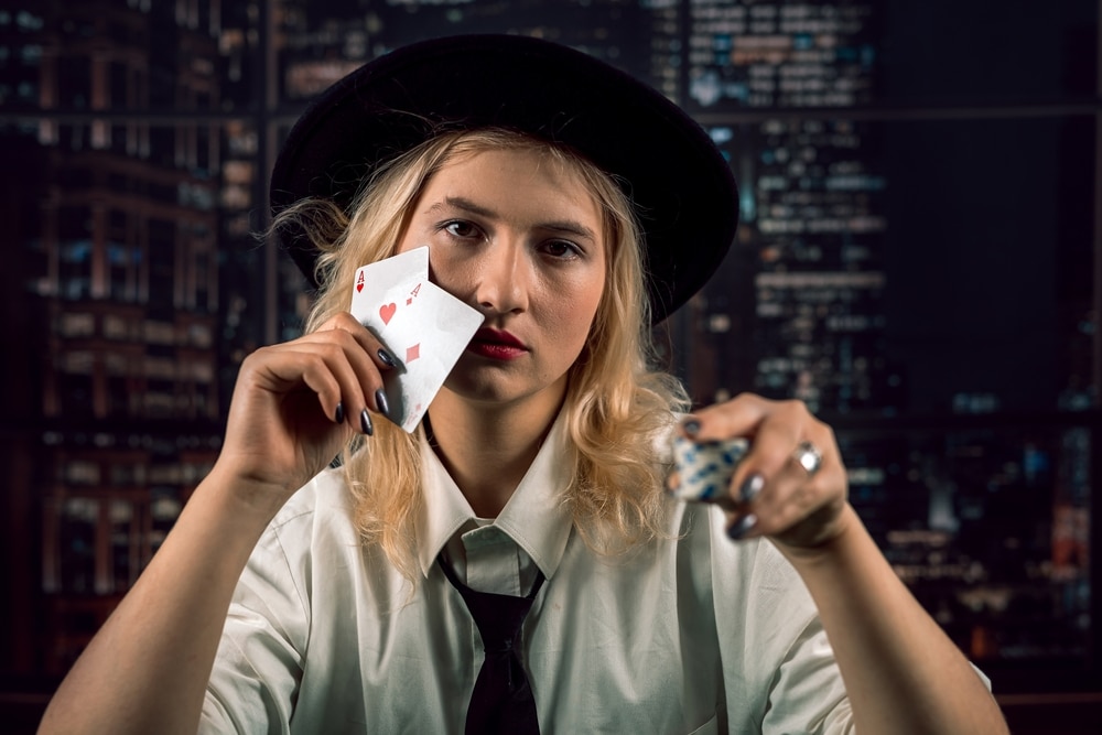 Woman with a poker face holding pocket aces and poker chips